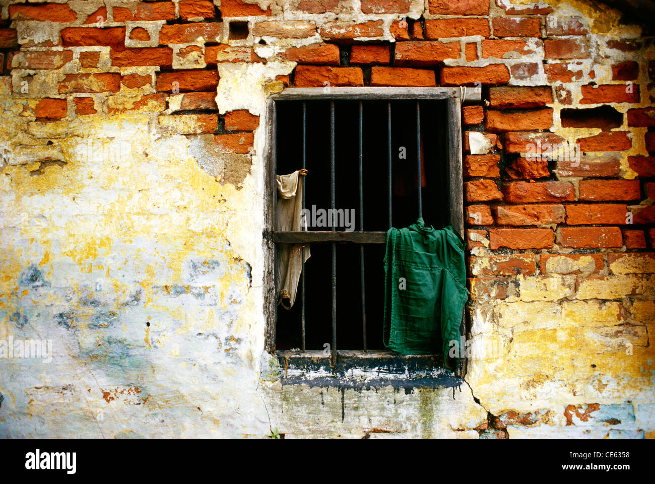 open iron bar window on ruined damaged red bricks wall india Stock Photo