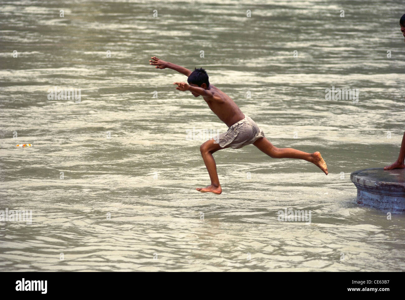 Boy jumping in the Ganges river at Rishikesh ; Uttar Pradesh ; India