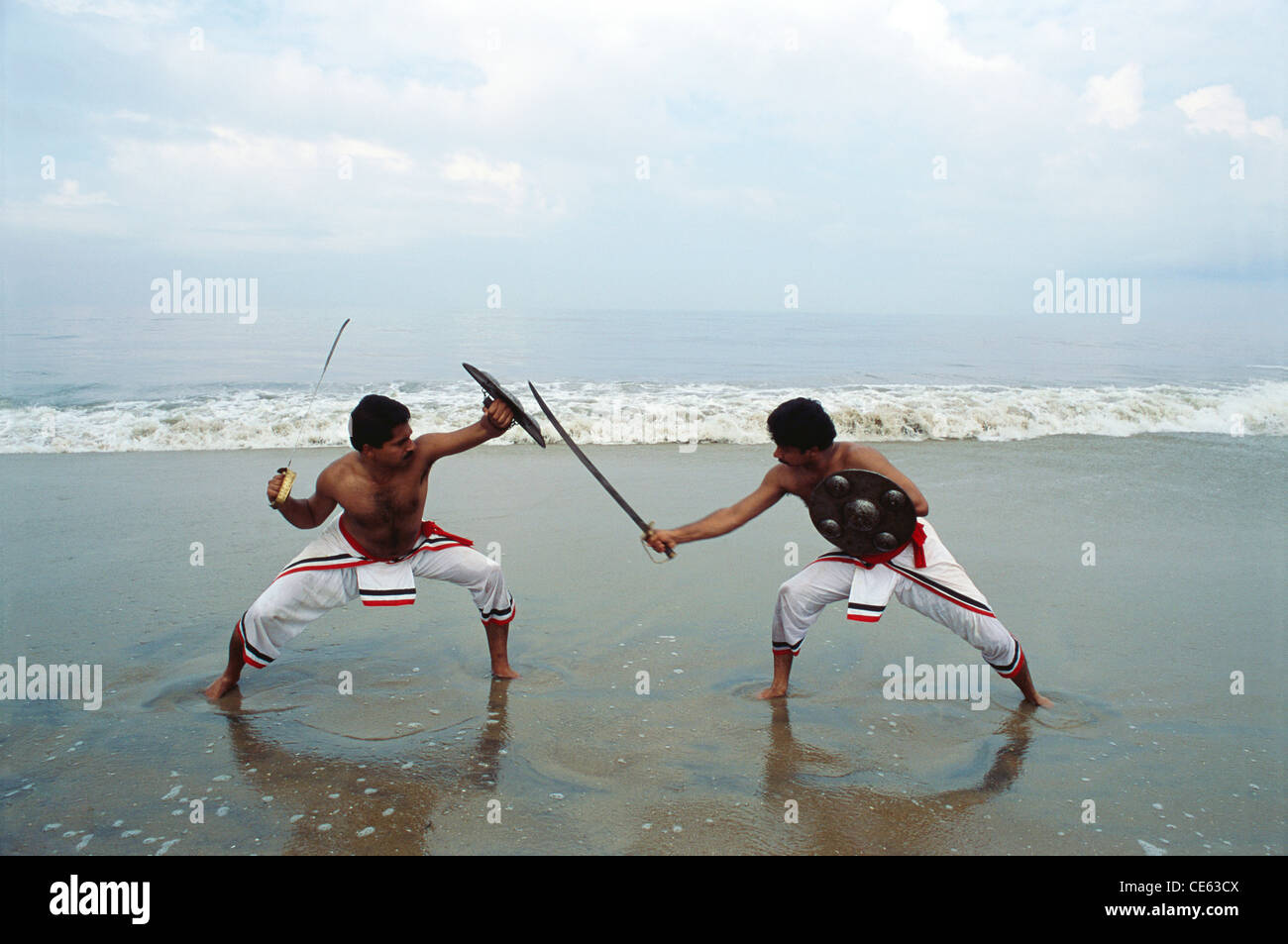 Kalaripayattu ; Kalari ; Indian martial art and fighting style with sword shield on beach ; Kerala ; India ; Asia ; Indian ; Asian ; MR#1 ; MR#777B Stock Photo