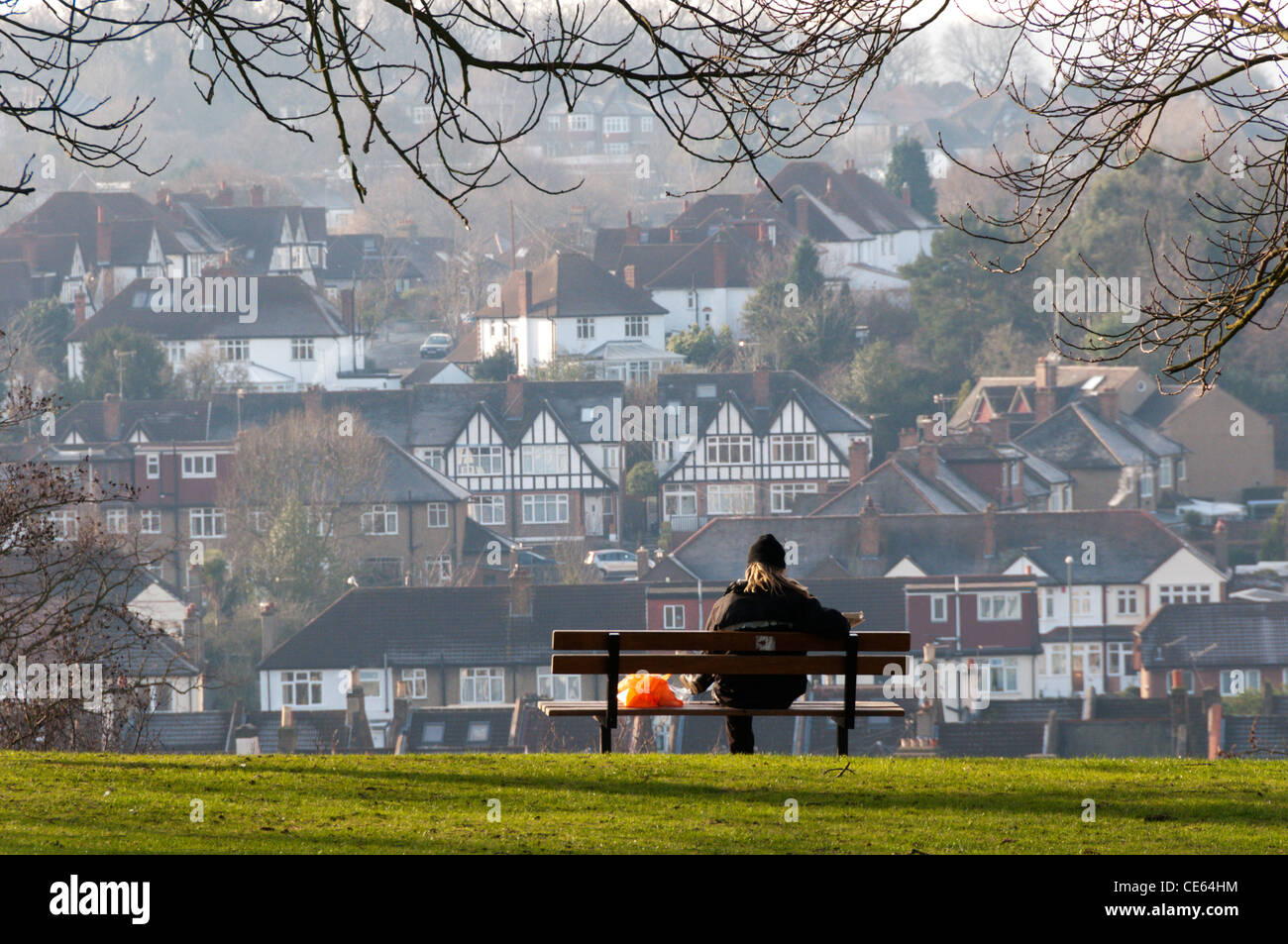 A person rests on a seat overlooking the South London suburb of Shortlands and reads a newspaper. Stock Photo