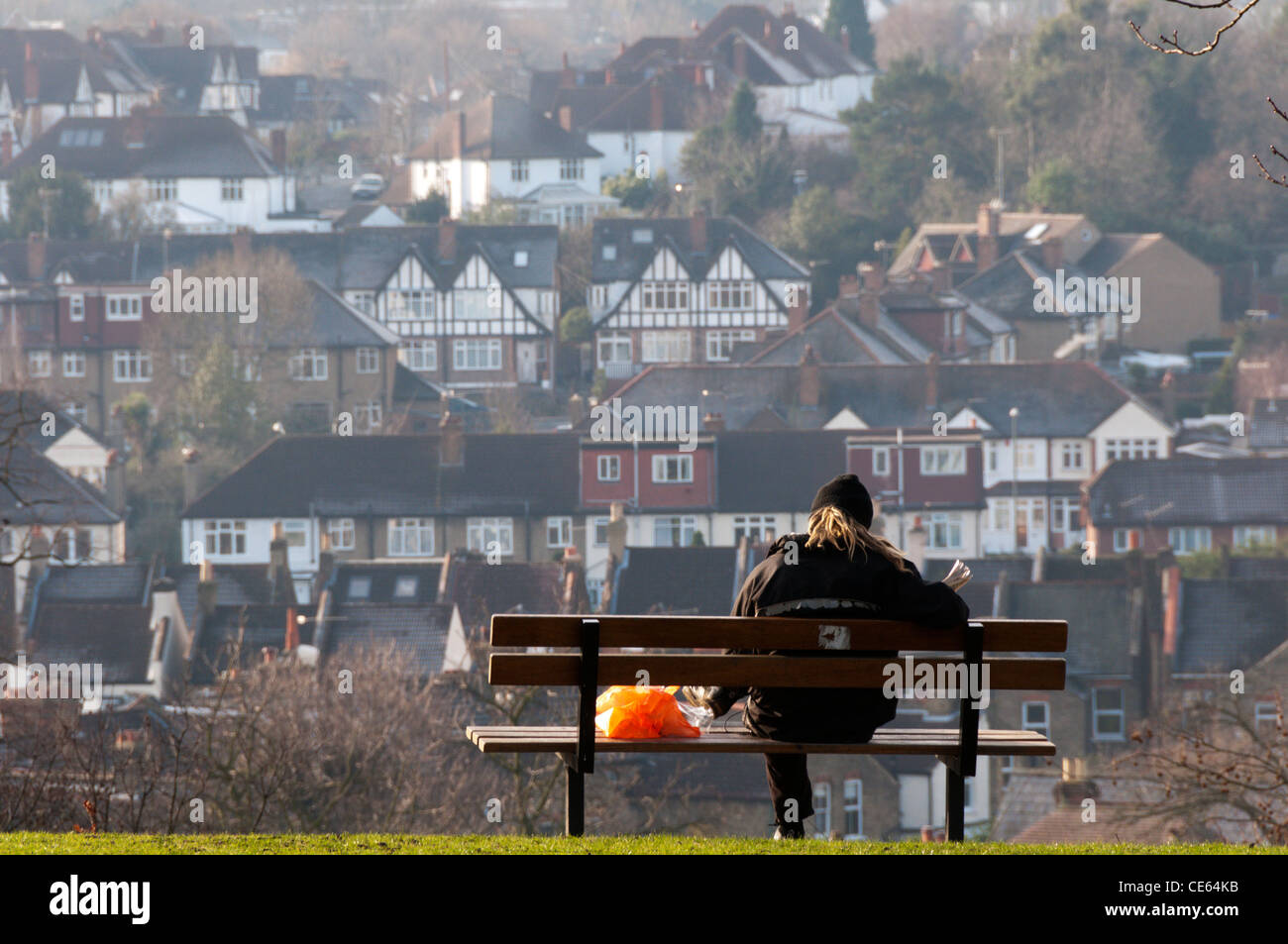 A person rests on a seat overlooking the South London suburb of Shortlands and reads a newspaper. Stock Photo