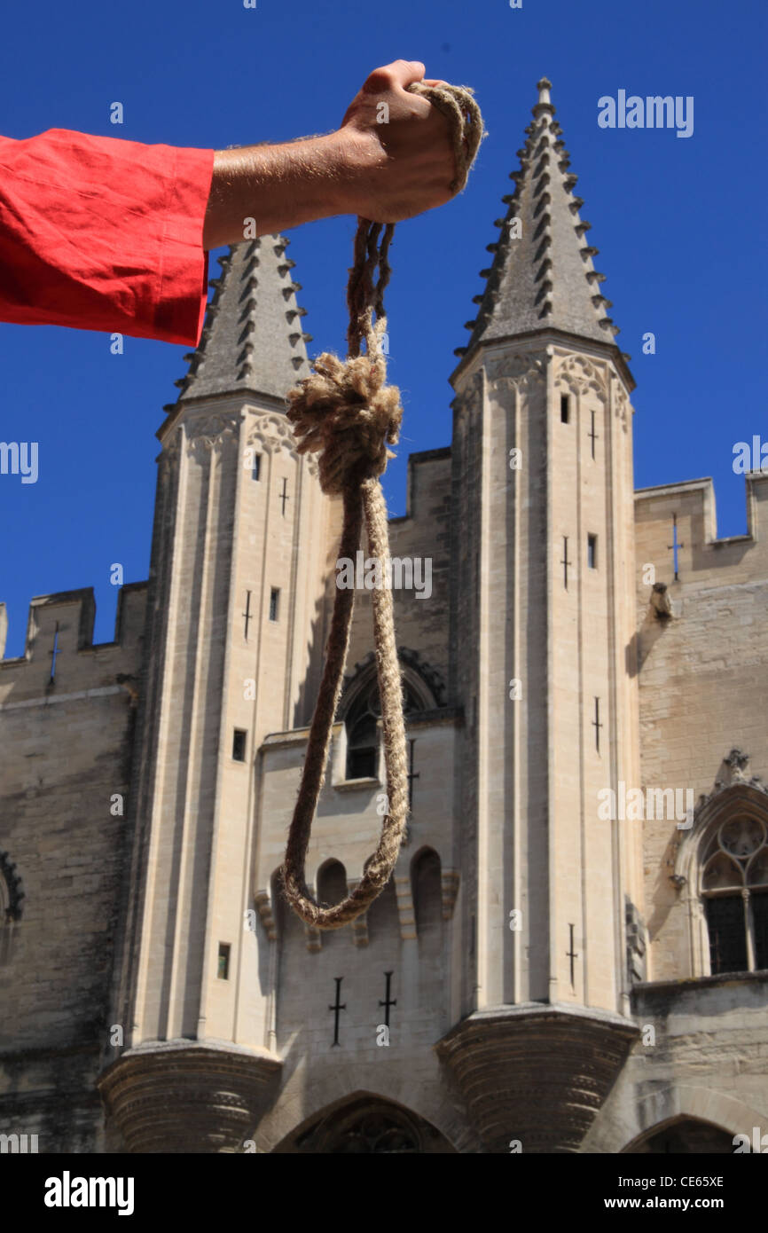 An executioner is showing a noose in front of the Palace of the popes in Avignon, France, historic seat of Inquisition Tribunal Stock Photo