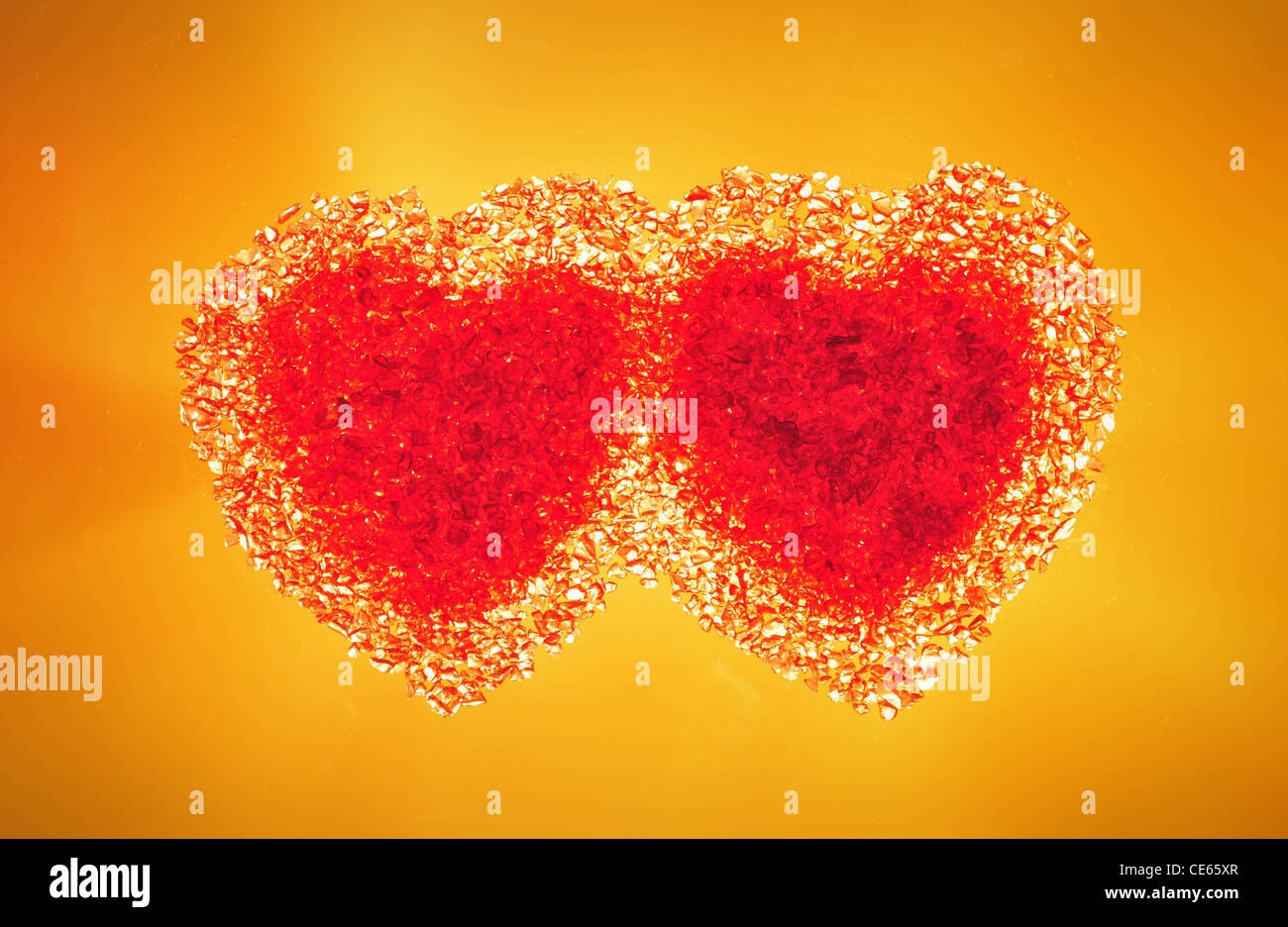 Two hot red hearts on a warm yellow background. Stock Photo