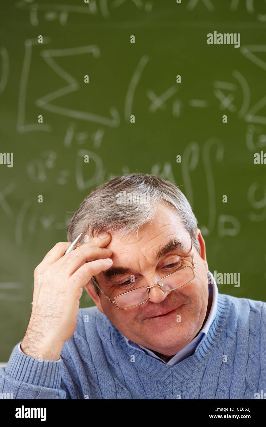 Portrait of aged teacher thinking of idea with blackboard on background ...