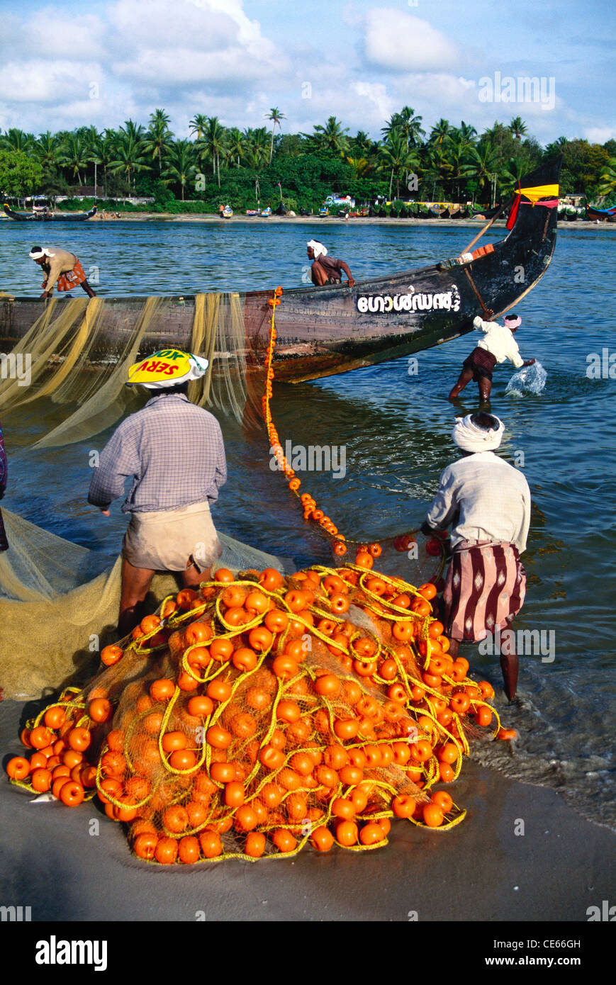 Fishermen pulling fishing net from fishing boat ; Thottappally