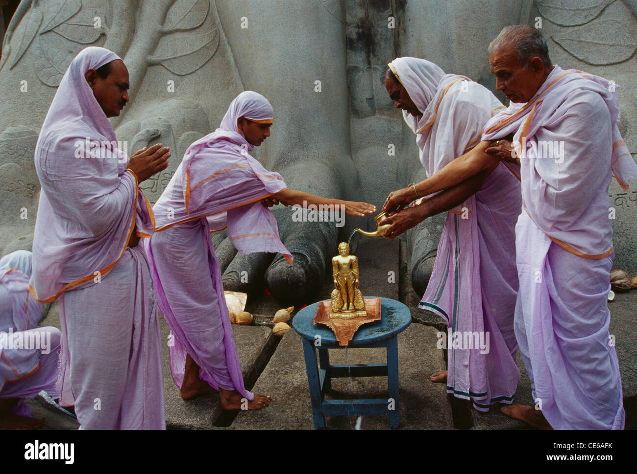Jain sadhvi pouring water on miniature statue of jain saint Gomateshwara in Shravanbelagola ; Karnataka ; India Stock Photo