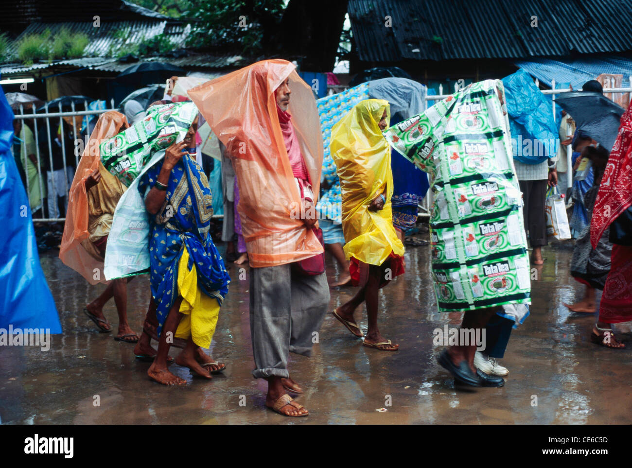 people wearing plastic sheets as rain coats walking in monsoon rain season in Kumbh fair mela