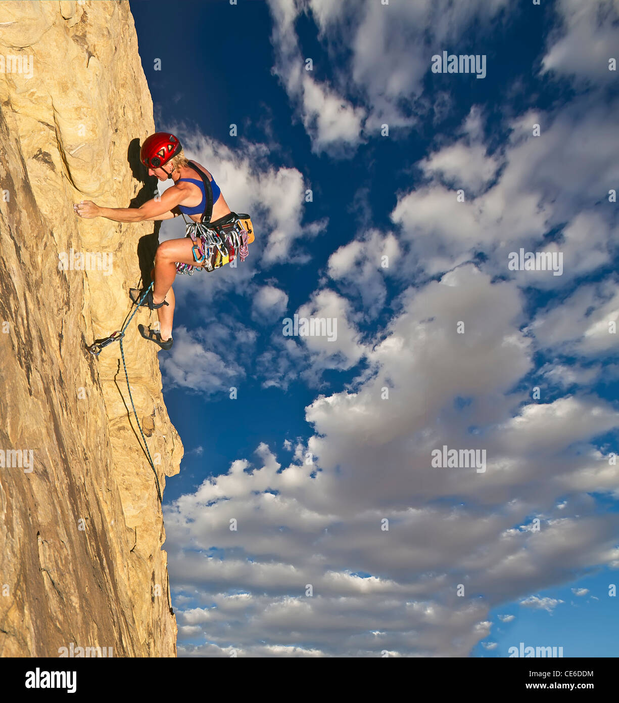 Female climber struggles up the edge of a challenging cliff Stock Photo