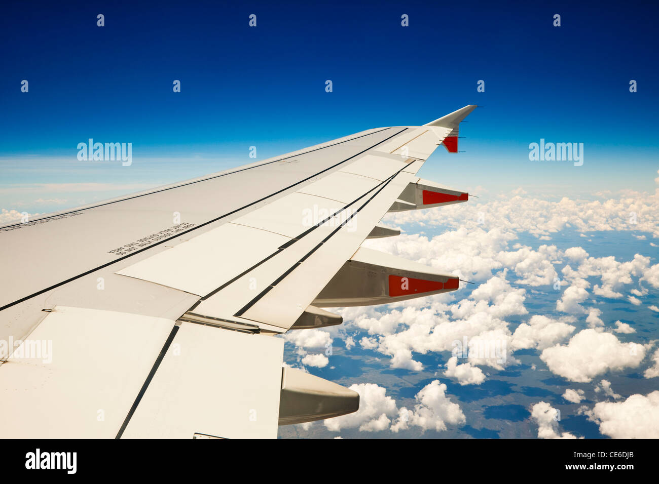 View of jet aircraft wing above the clouds. Stock Photo