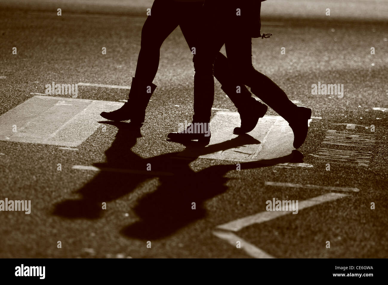 The legs of two females as they cross a road at a zebra crossing Stock Photo