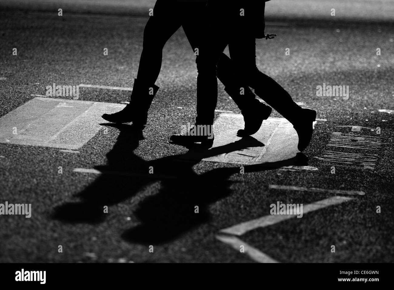 The legs of two females as they cross a road at a zebra crossing Stock Photo