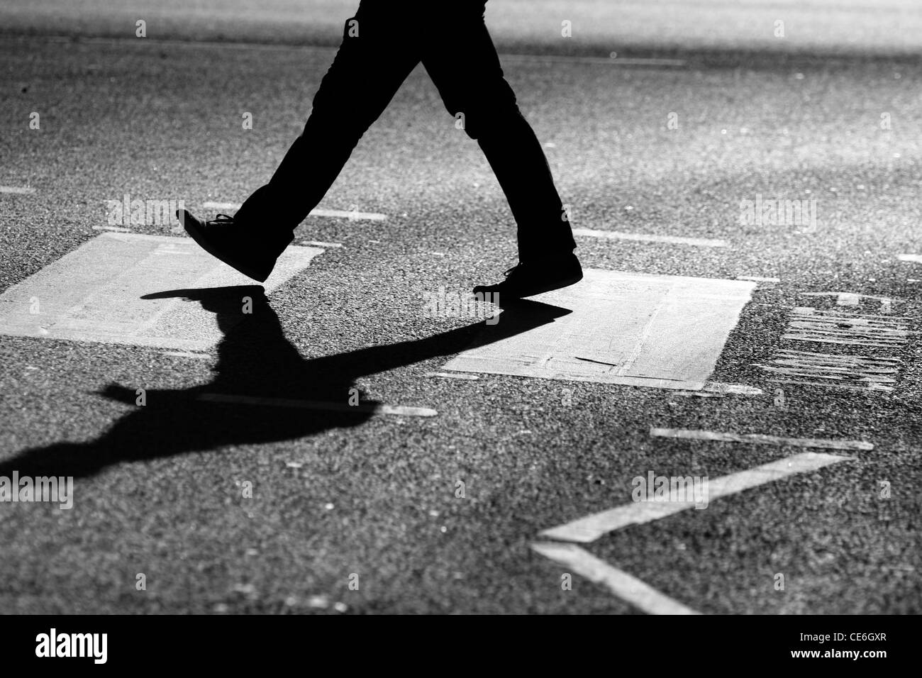 The legs of a man as he crosses a road at a zebra crossing Stock Photo