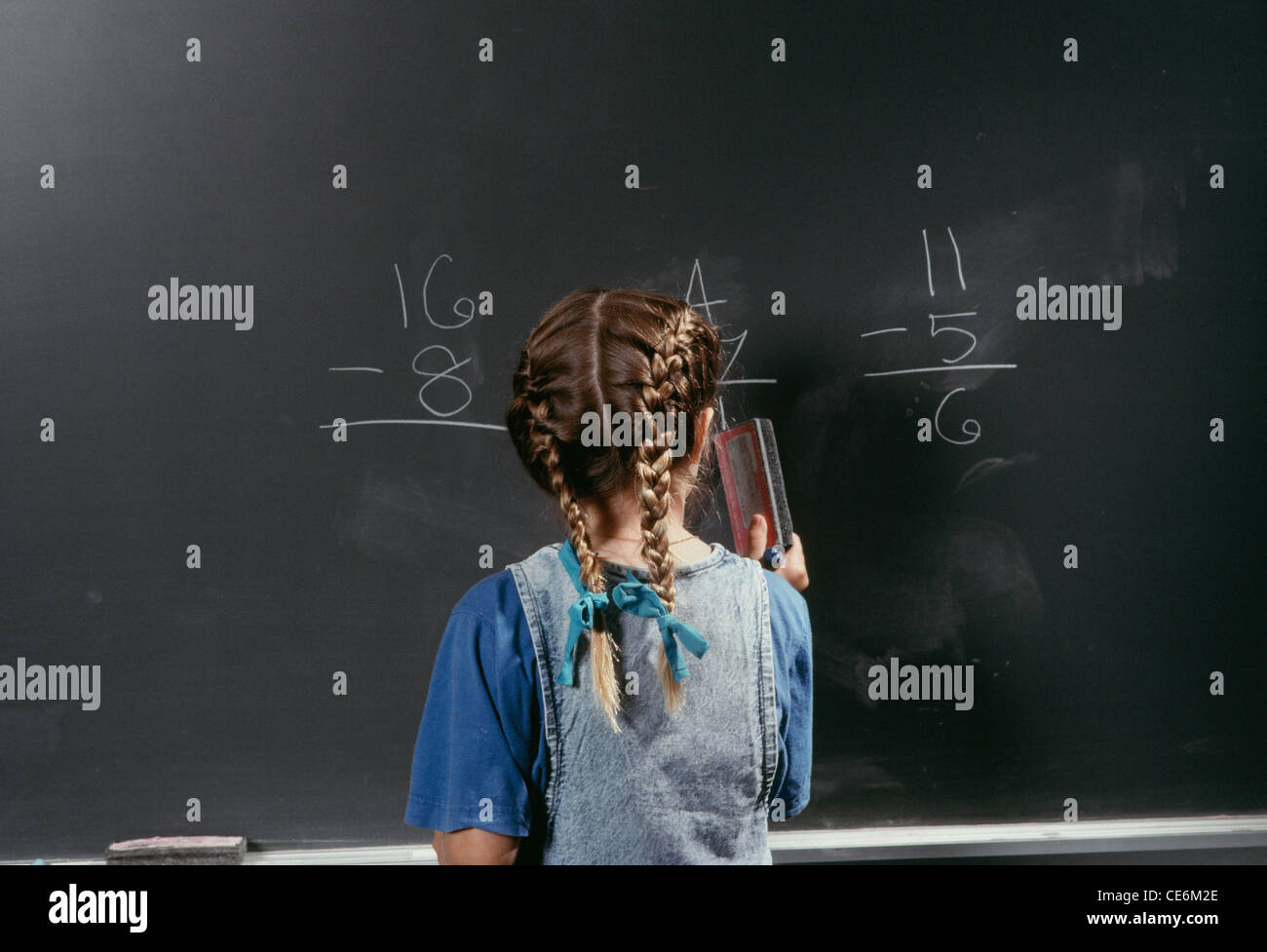 Young Schoolgirl at the blackboard with her arithmetic lesson. Stock Photo