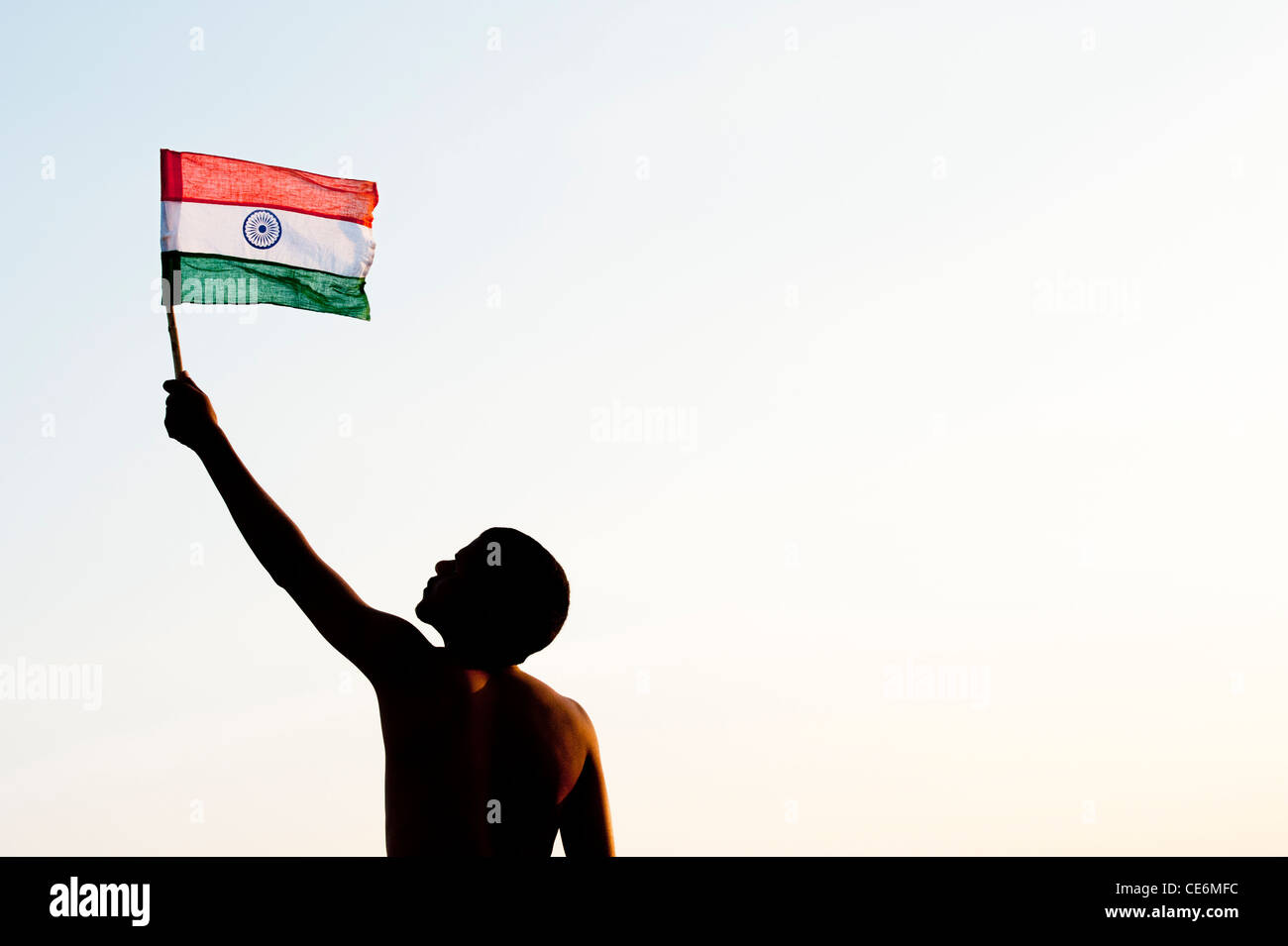 Indian man holding an Indian flag against at sunset in India. Silhouette Stock Photo