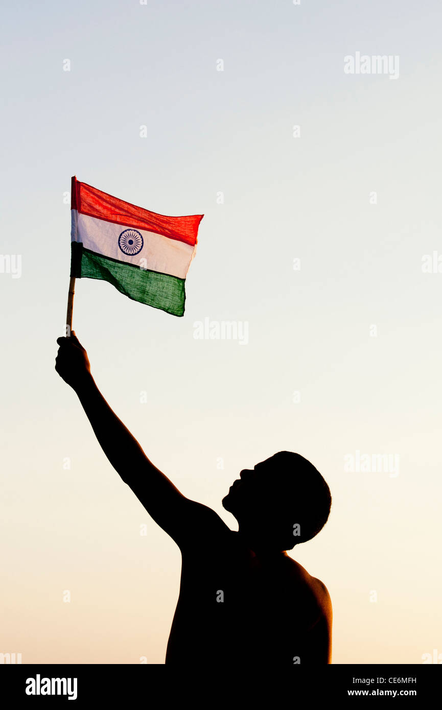 Indian man holding an Indian flag against at sunset in India. Silhouette Stock Photo