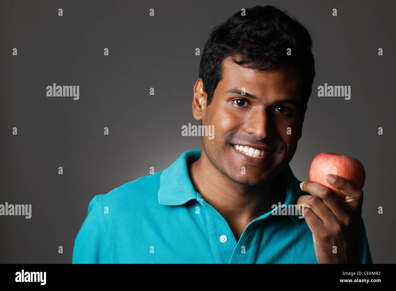 Head shot of Indian man holding apple and smiling Stock Photo - Alamy
