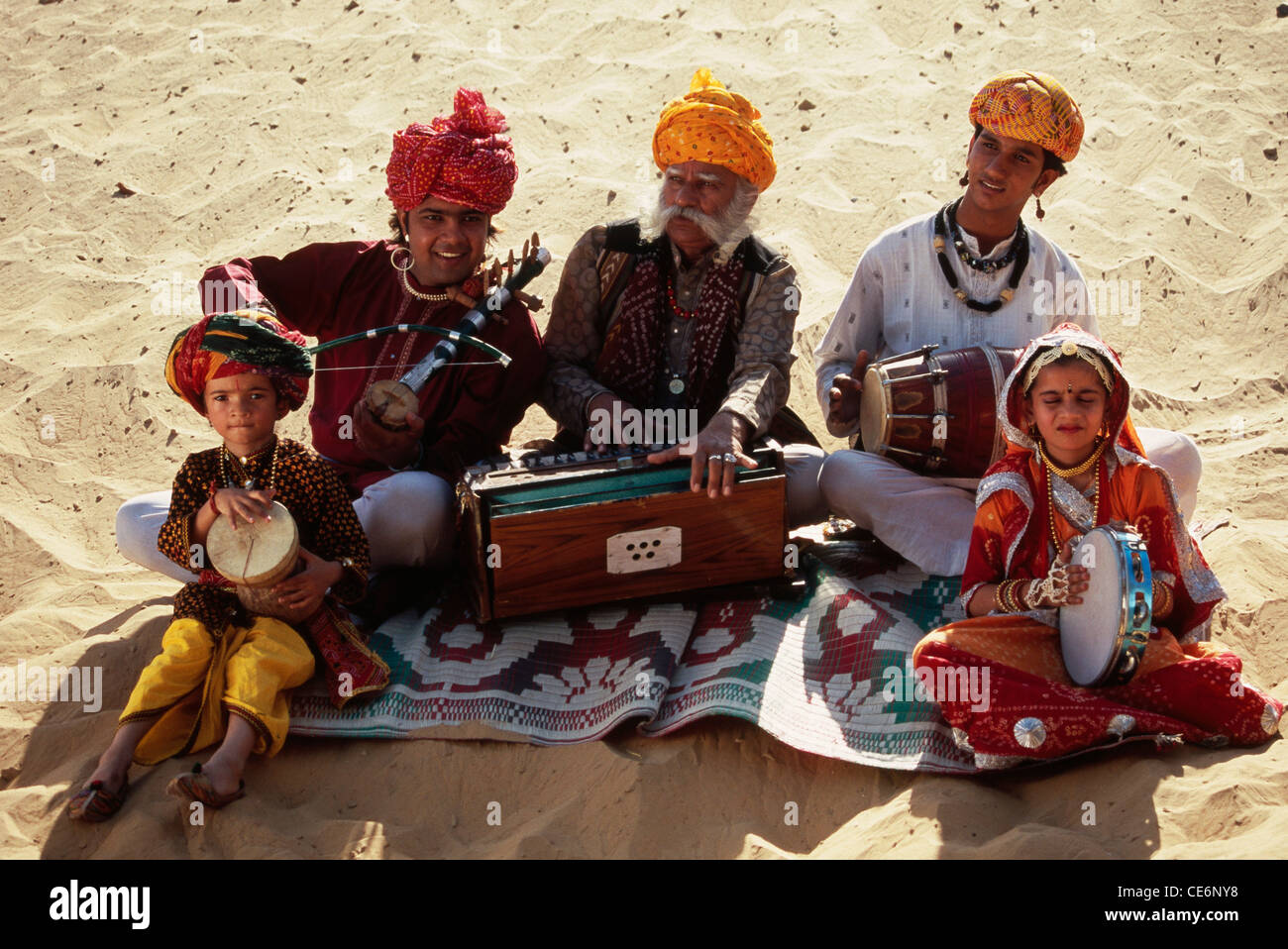 Indian folk musicians family playing musical instruments in desert
