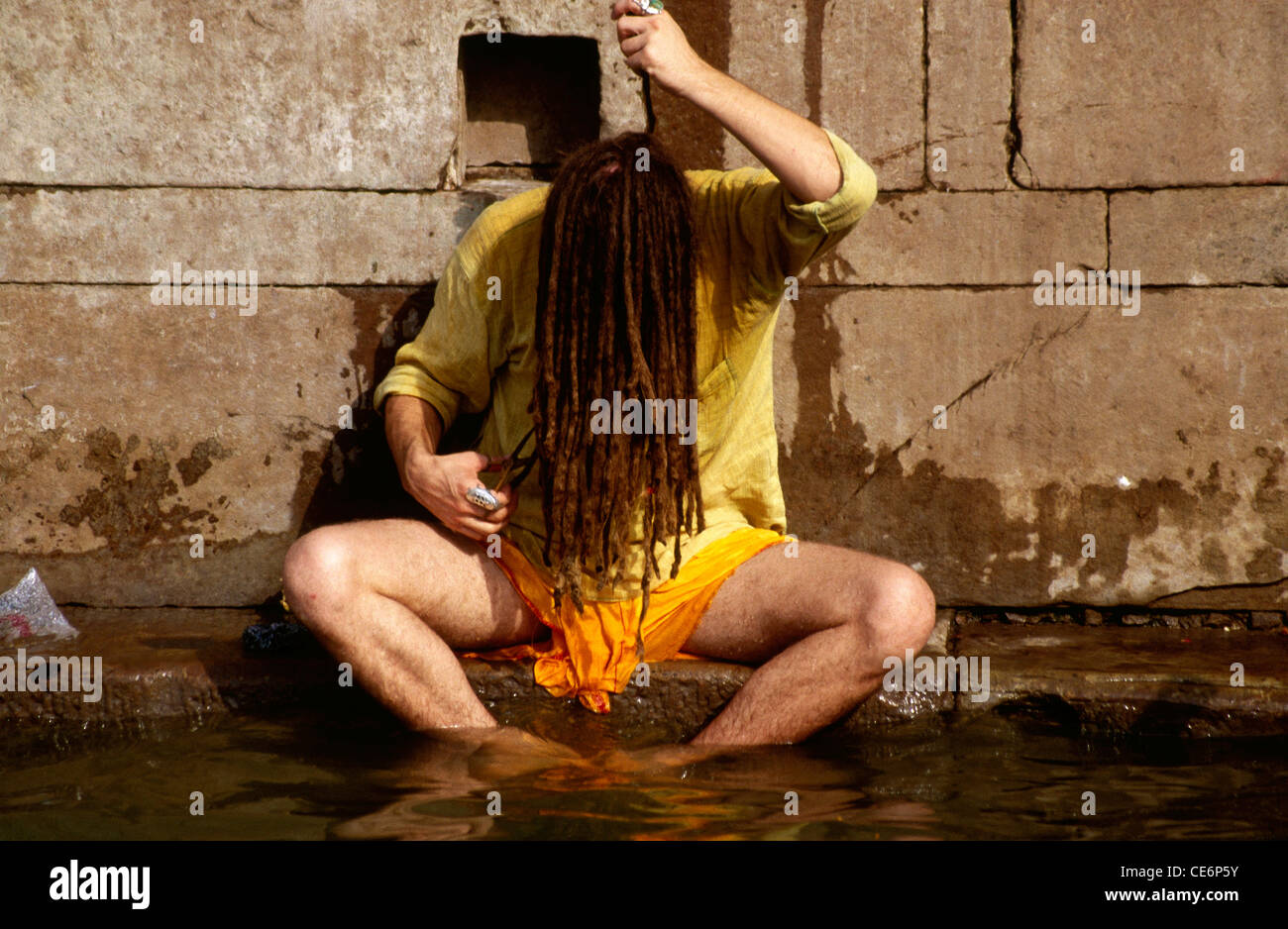Man with long matted hair face covered washing in Ganges river ; Varanasi ; Uttar Pradesh ; India Stock Photo