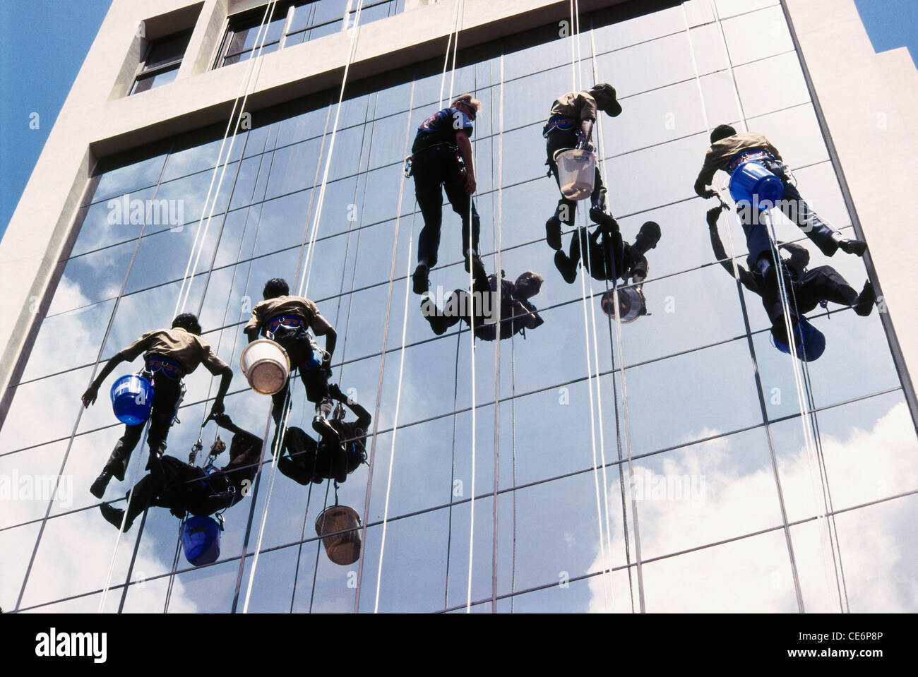 Indian window cleaners working cleaning on glass building ; Bombay