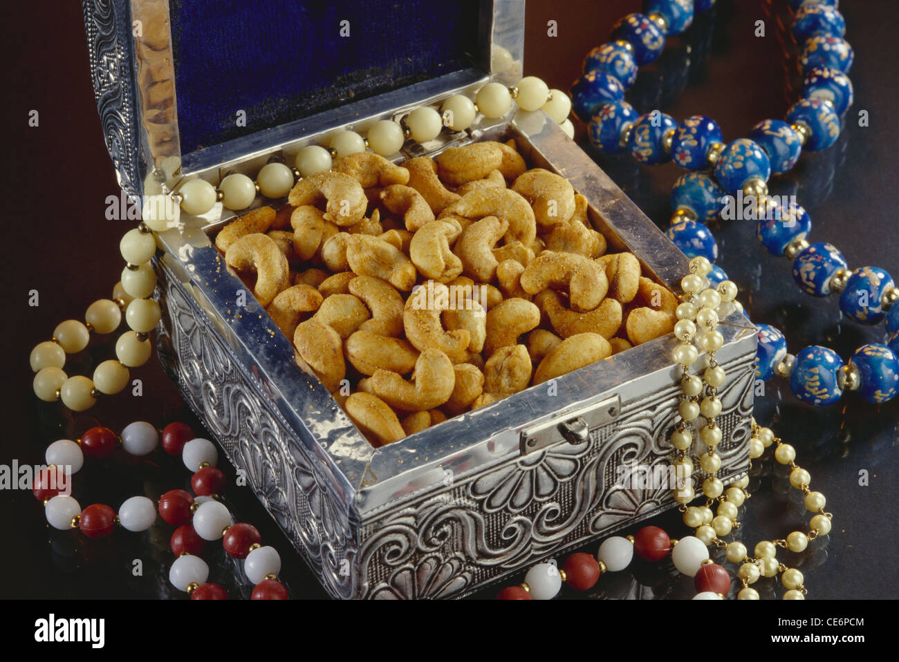 masala flavored Cashew nuts in silver metal box with beads on black