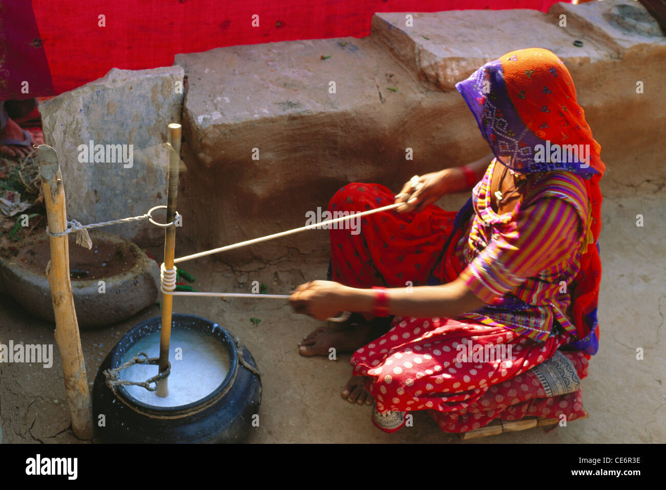 Indian rural woman churning buttermilk ; jodhpur ; rajasthan ; india ...