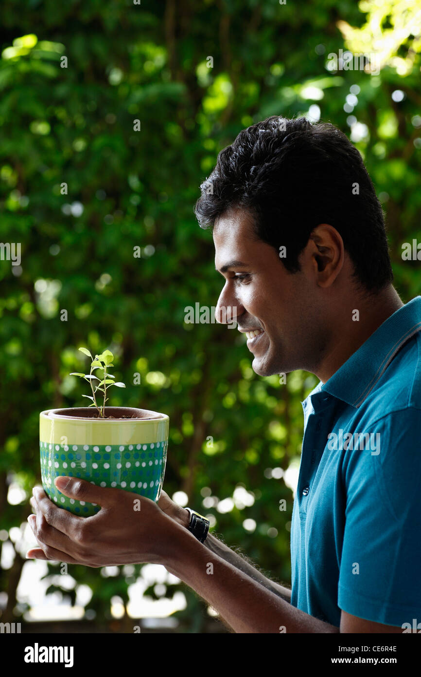 Profile of man holding potted plant and smiling Stock Photo - Alamy