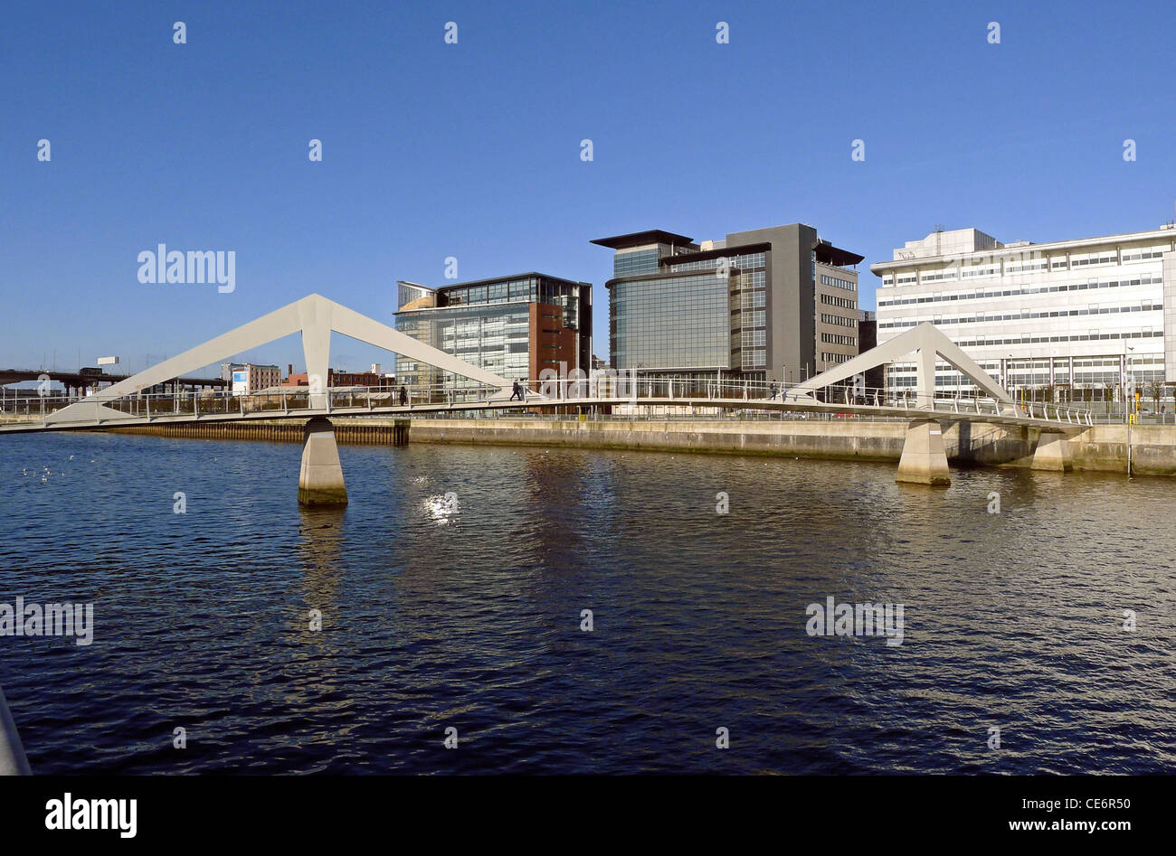 A line-up of buildings on either side of the pedestrian Tradeston Bridge along Atlantic Quay on the River Clyde in Glasgow Stock Photo