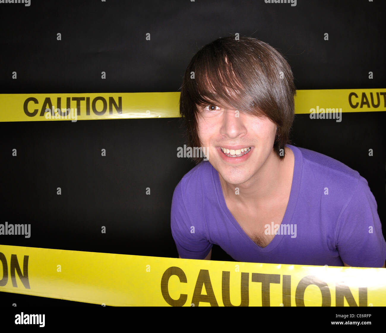 Young Man With An Uneasy Smile Surrounded By Caution Tape Stock Photo Alamy