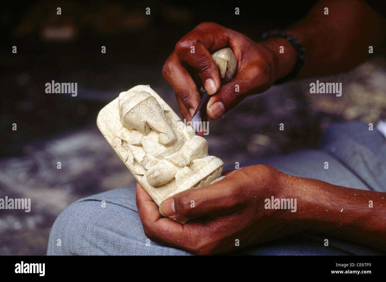 MAA 85114 : man carving lord ganesh idol from the root of white madar plant india Stock Photo