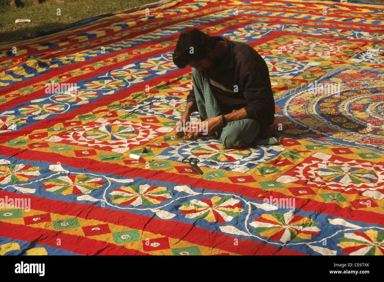 Man cleaning finishing applique patchwork pipli floor covering carpet ; peepli ; Pipili ; Puri ; orissa ; odisha ; india ; asia Stock Photo