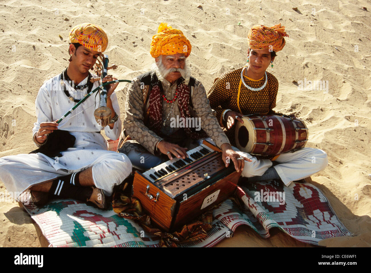 Rajasthani folk musicians playing musical instrument harmonium violin drum desert Jaisalmer Rajasthan India - MR#657A Stock Photo