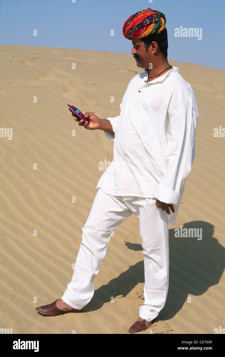 MMN 84006 : South Asian Indian rajput man turban kurta pyjama mobile phone desert jaisalmer rajasthan India Stock Photo