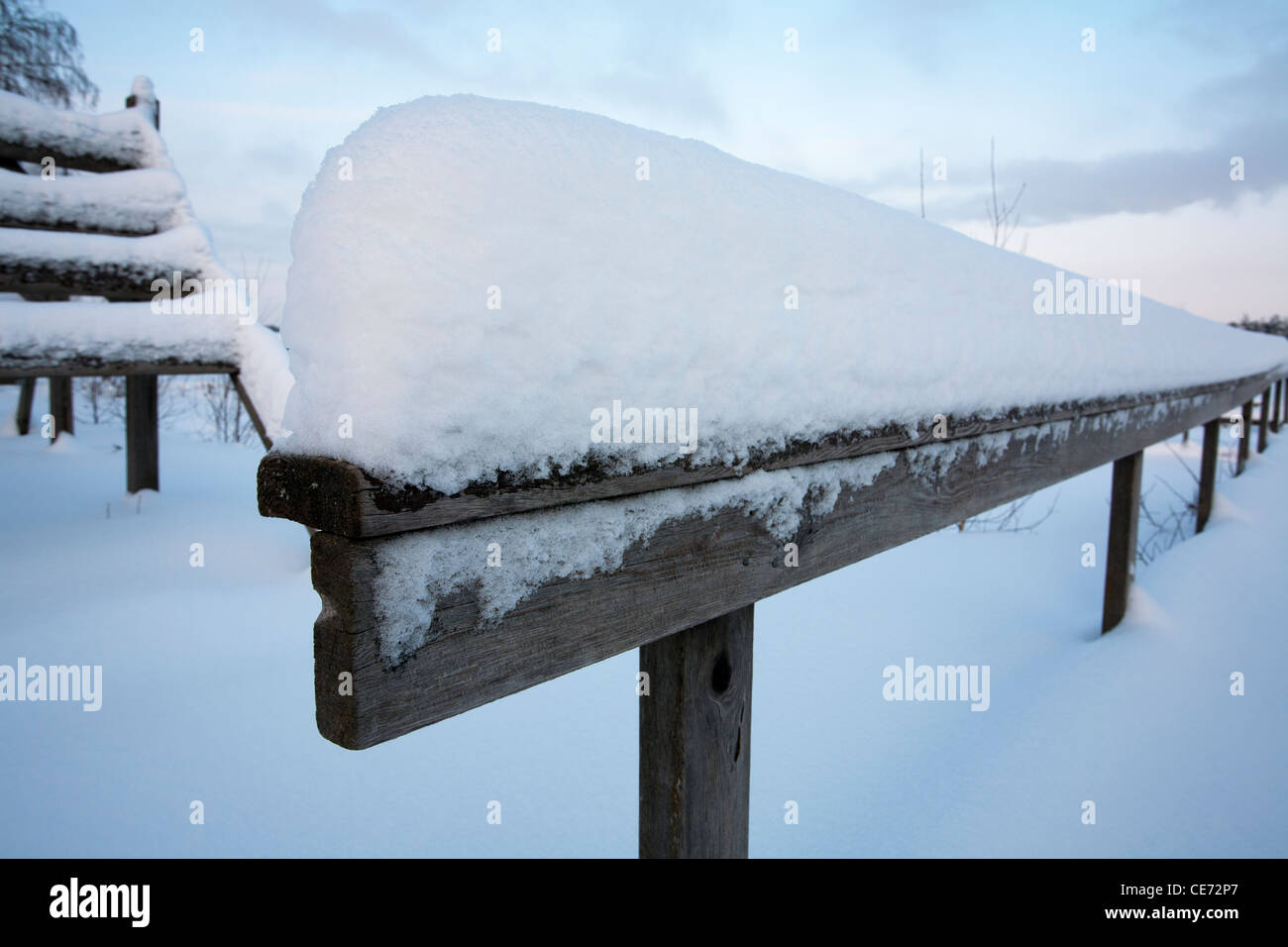 weathered old wooden handrail in snow, Finland Stock Photo