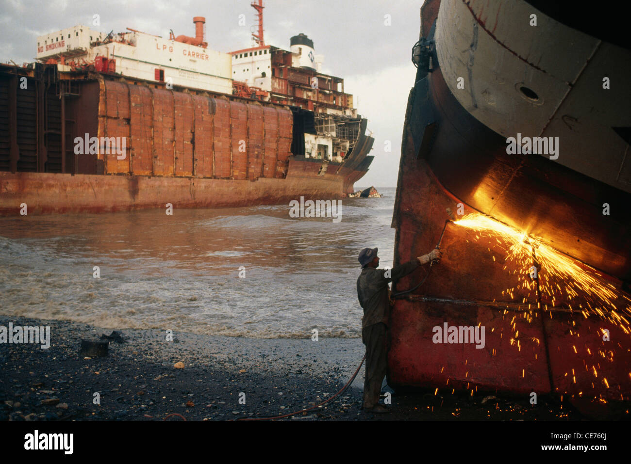 Indian man gas cutting steel plate in Alang ship breaking yard Gujarat India Asia Stock Photo