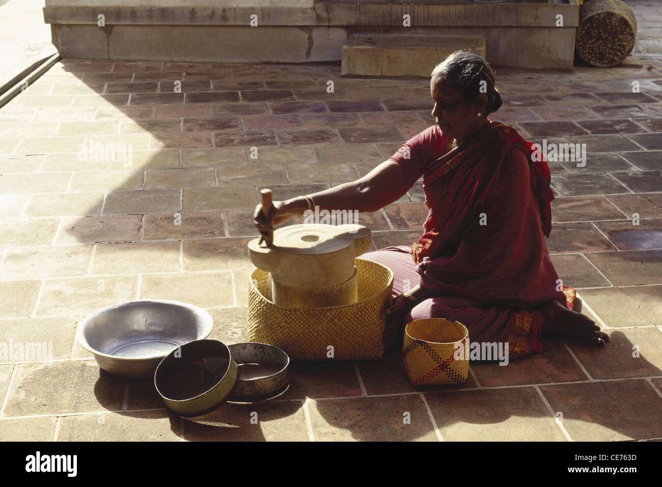 Indian women grinding rice on hand grinding stone ; Chettinad ; Chettinadu ; Sivaganga district ; Tamil Nadu ; India ; Asia ; Indian ; Asian ; MR#777A Stock Photo
