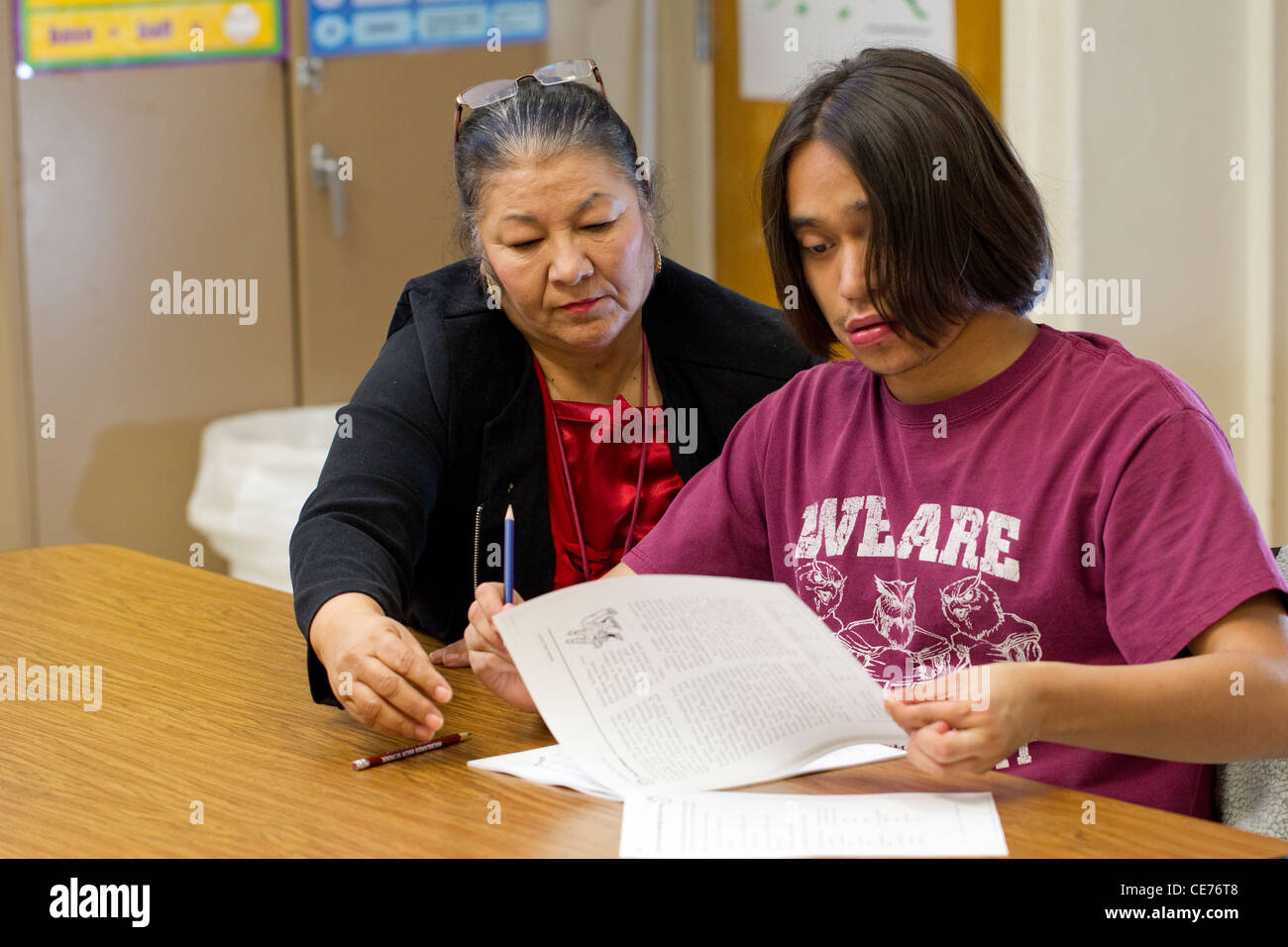Hispanic female teacher in class works one-on-one with autistic teenage high school students Stock Photo