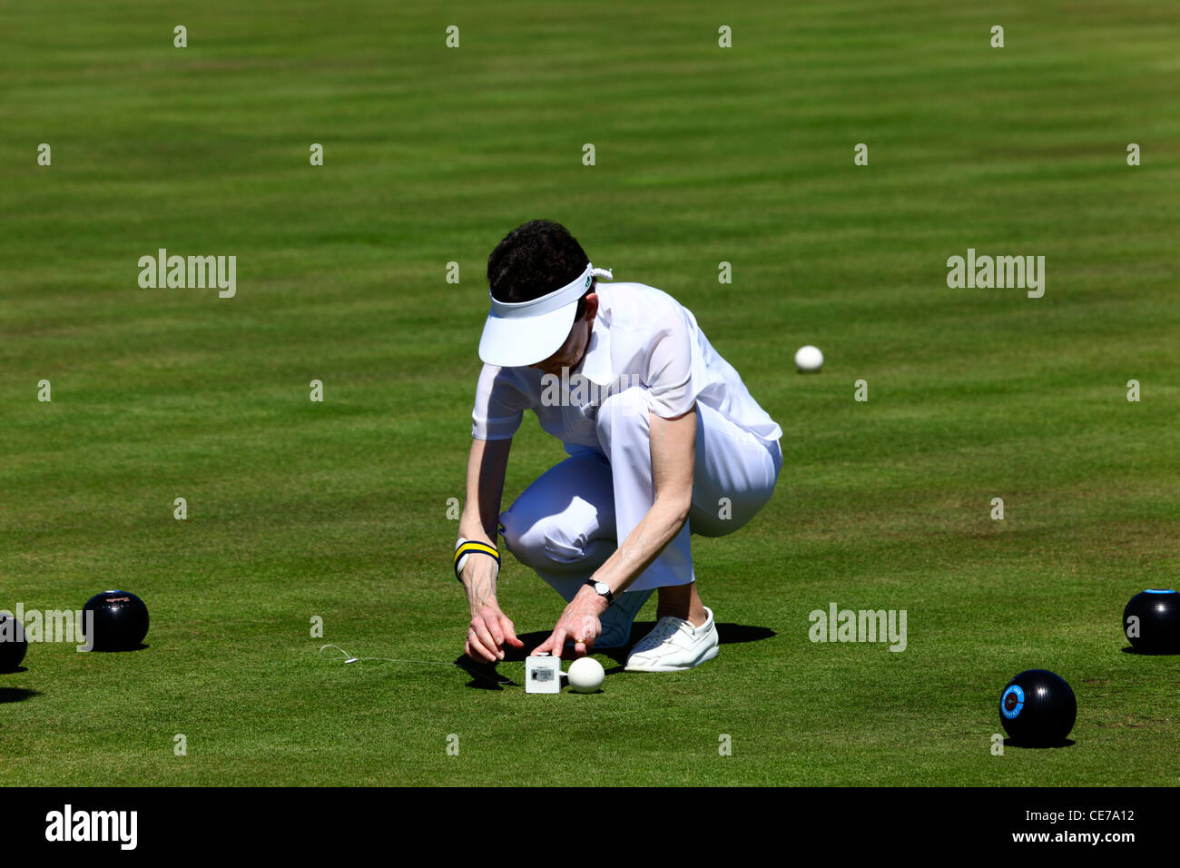 Lady measuring distance of woods from jack after a game of bowls , Southborough Common , Tunbridge Wells , Kent , England Stock Photo