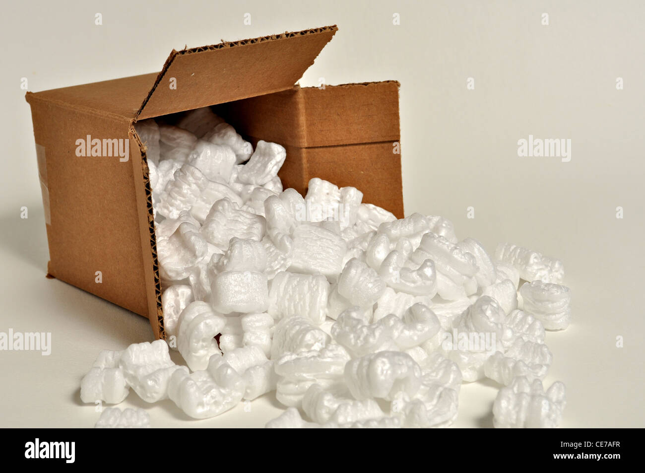 A cardboard box is laying on its side with shipping peanuts spilling out. Stock Photo