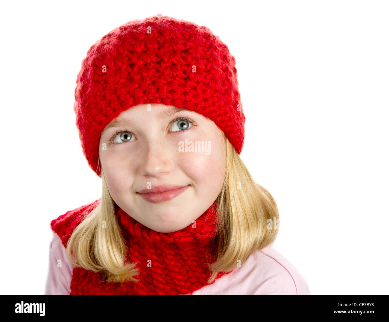 a cute girl wearing a red knit winter hat and a red knit scarf. portrait isolated on a white background. Stock Photo