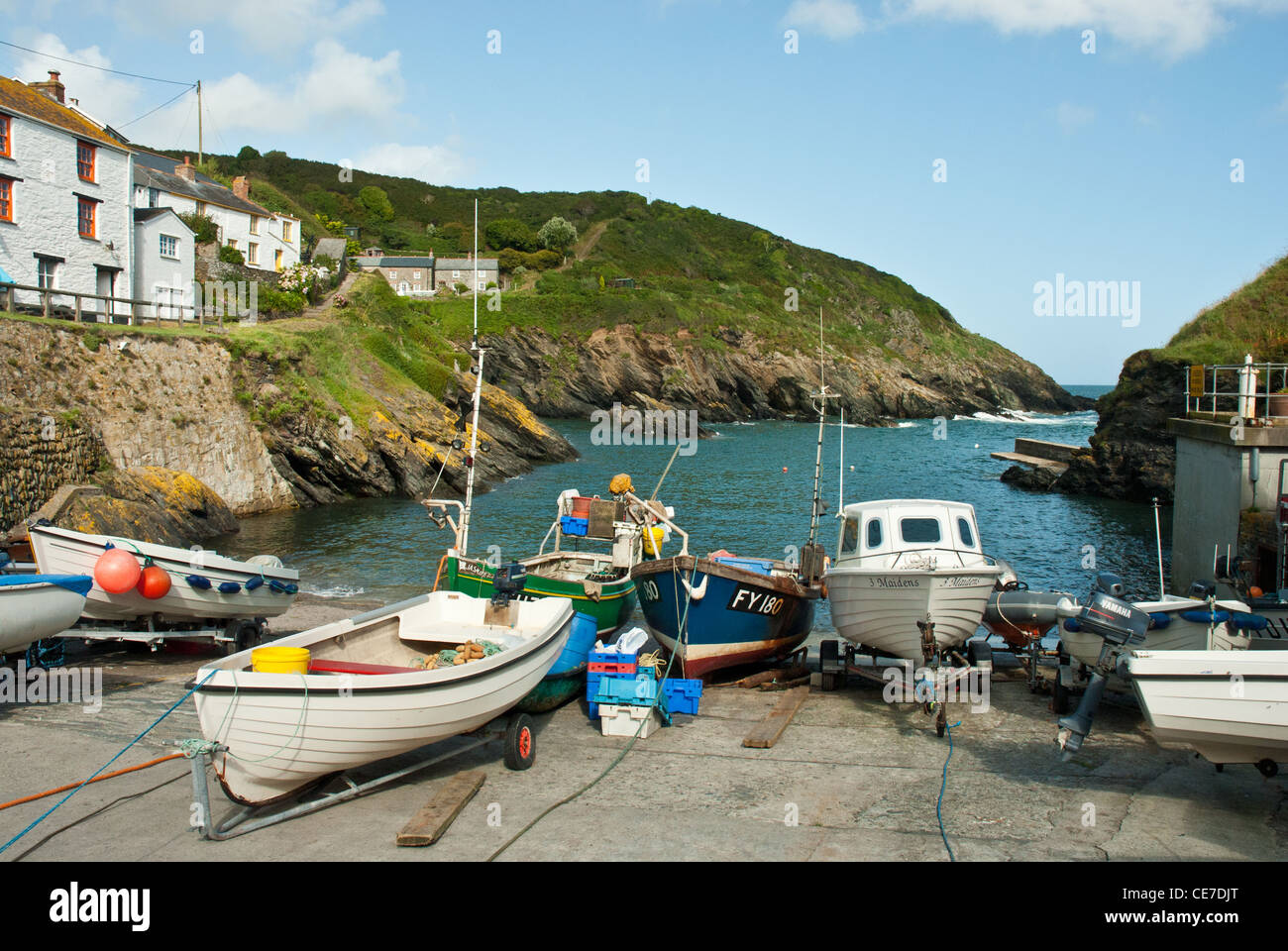 Portloe Cove and Harbour with small boats, traditional fishing cottages, blue sea and sky. Stock Photo