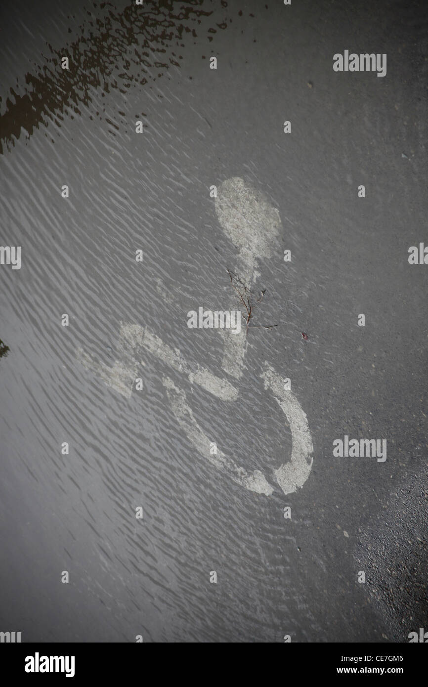 Painted handicapped parking sign on asphalt covered with water on a rainy day Stock Photo