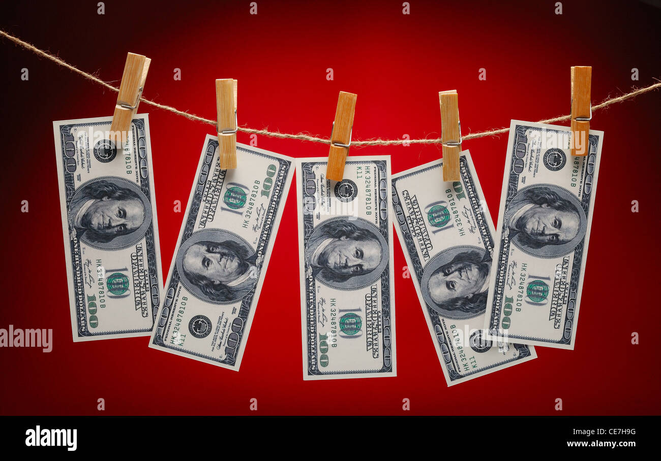US Dollars Hanging on Rope with Clothespins on red background Stock
