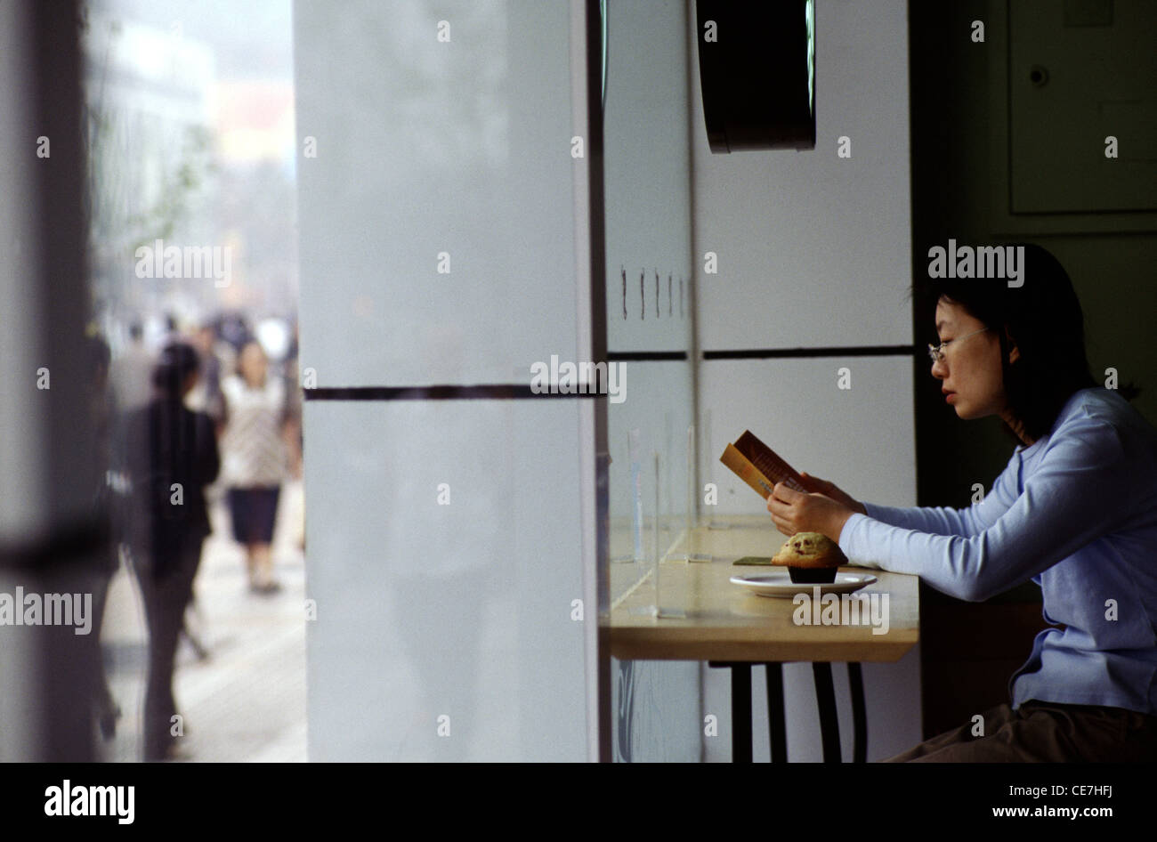 A Chinese woman reading the menu in a coffee shop in Wangfujing pedestrian street located in Dongcheng District Beijing China Stock Photo