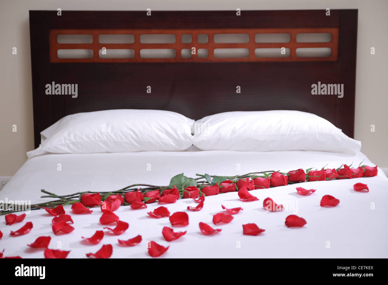 white hotel bed withe roses and petals on it Stock Photo