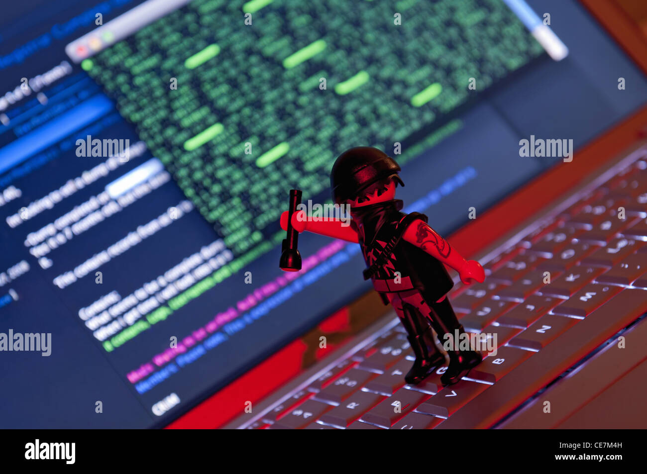 Playmobil Hacker dressed in dark clothing with torch about to steal information from laptop. Stock Photo