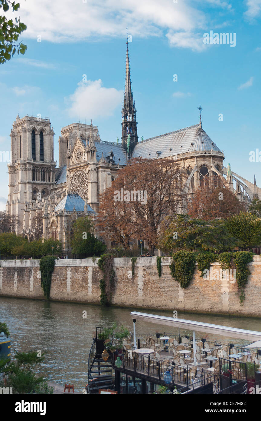 Vertical shot of the Notre Dame cathedral taken from across the seine, with a river boat cafe in the foreground. Stock Photo