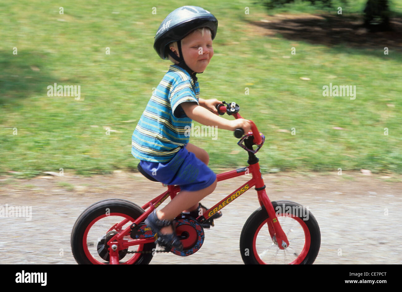 Cycling, young boy on bike with helmet and stabilisers, boy about 2+ years old. Stock Photo