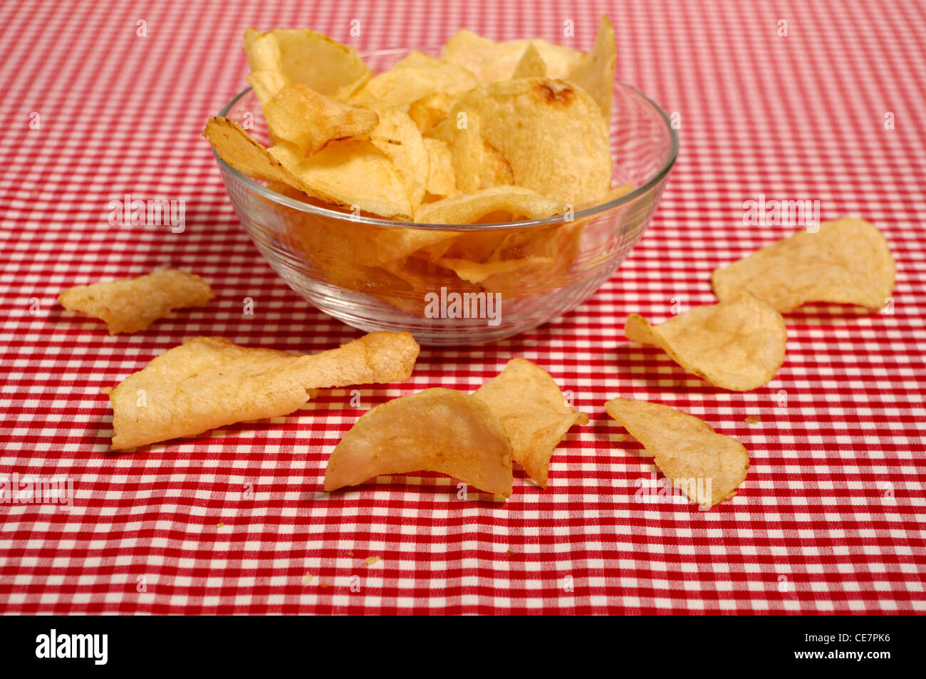 Potato chips in a glass bowl on a red and white check table cloth Stock Photo