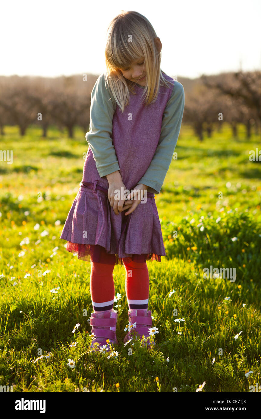 Cute little girl outdoors on a green field with flowers Stock Photo - Alamy