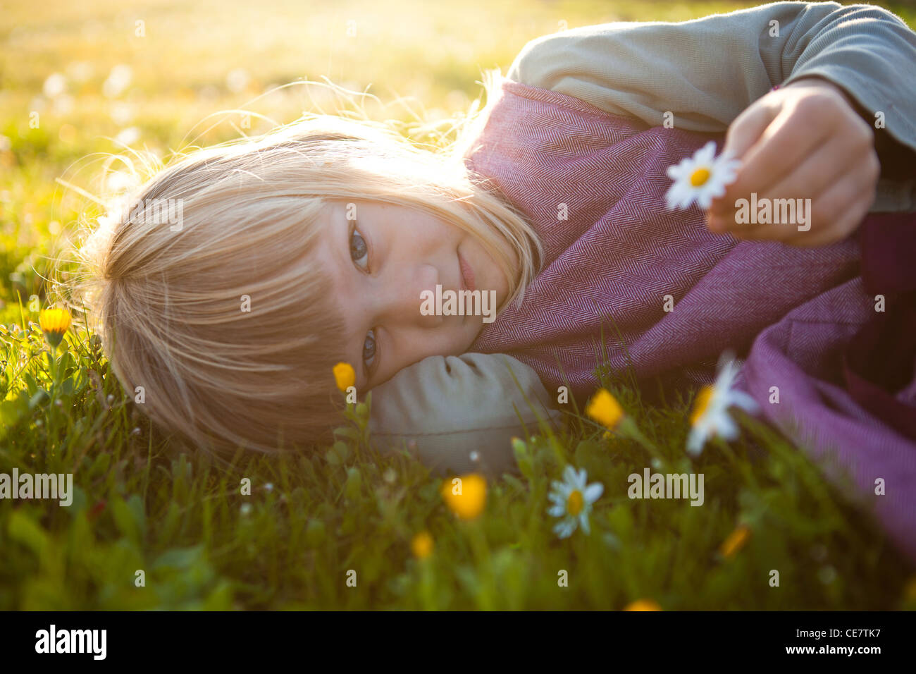 Cute little girl outdoors on a green field with flowers Stock Photo - Alamy